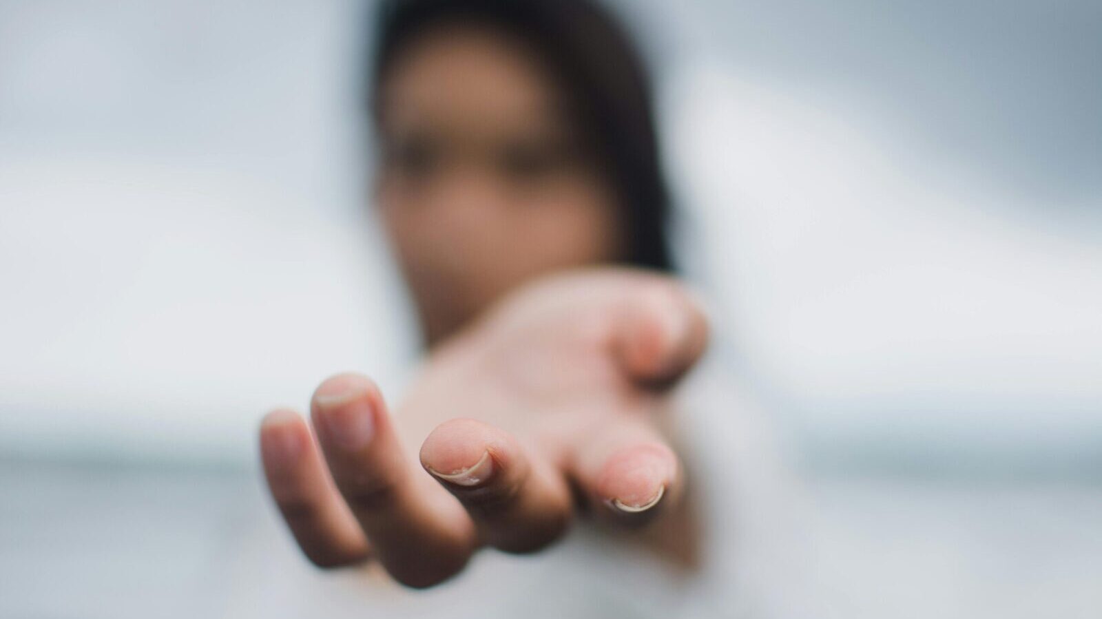 A soft focus image highlighting a reaching hand, symbolizing connection or help.